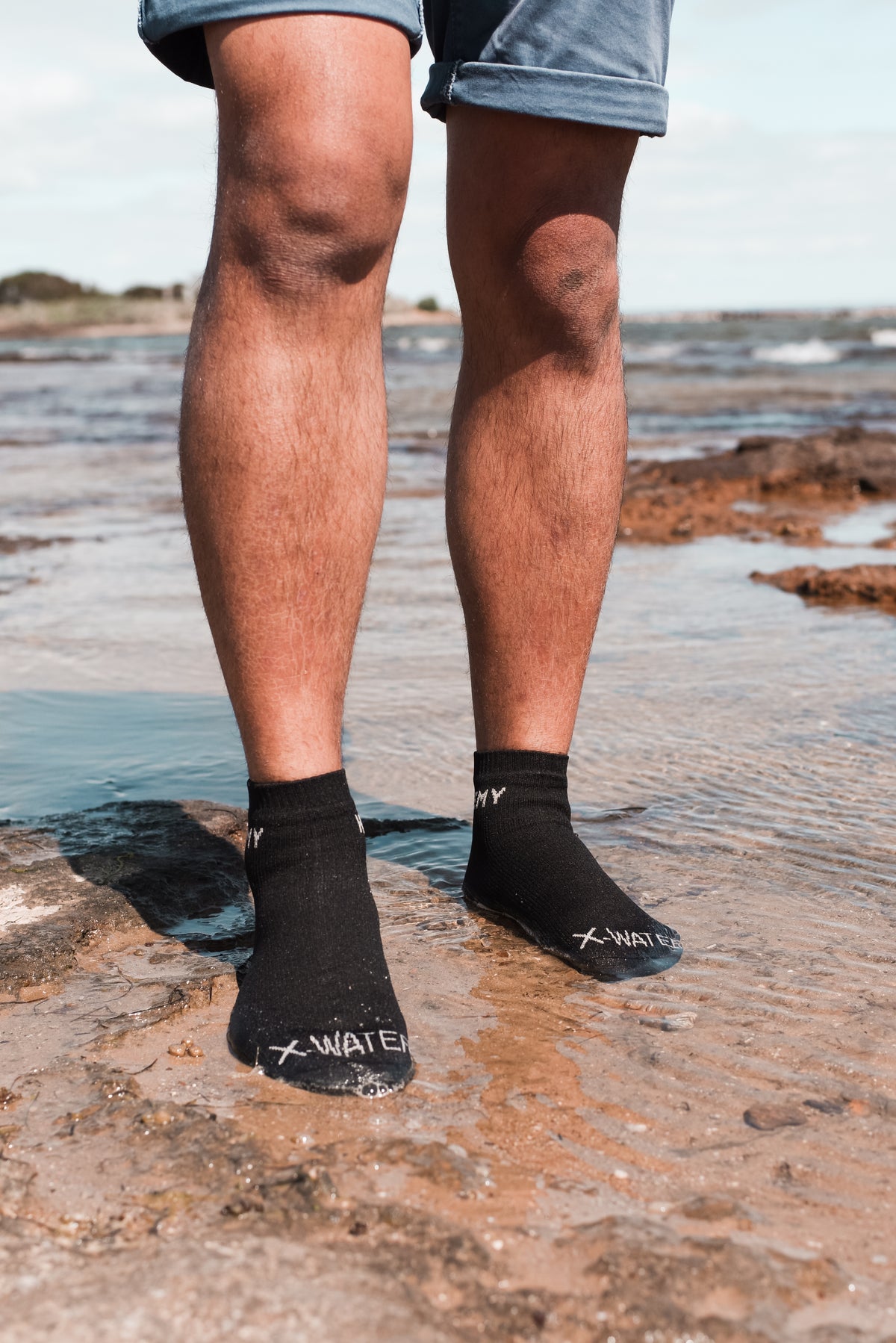Feet in HEMY waterproof socks standing in the sea